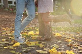 a girl in cowboy boots stands next to a guy