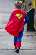 a boy in a hero costume is running down the street