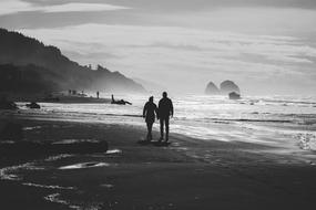 Black and white photo of the couple on the beautiful, sandy beach with mountains