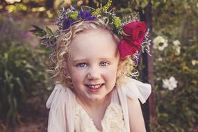 happy little girl with flowers in her hair on a blurred background