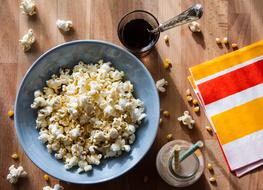 Popcorn in the blue bowl, drinks and colorful cloth, on the wooden surface