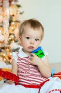 Baby girl sits near christmas tree