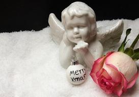 Beautiful, white angel with the white and black Christmas bauble, near the pink and white flower