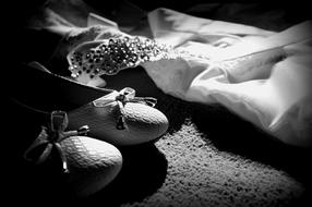 Black and white photo, with the close-up of the patterned wedding dress and shoes of the bride