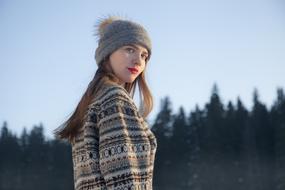 girl with red lips and in a winter hat posing in nature