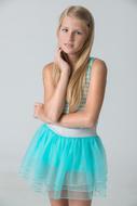 Portrait of the blonde girl in turquoise and white dress, posing at white background