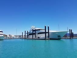 White yacht, in the port, among the beautiful, turquoise water, at blue sky on background