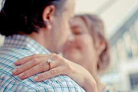 wedding ring on a woman's hand on a man's shoulder