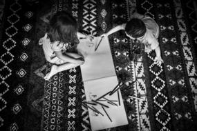 Black and white photo of the kids, drawing on the notebook