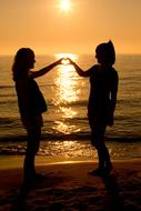 girls and heart at sunset on the coast