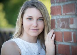 Portrait of a smiling blonde girl near the brick building