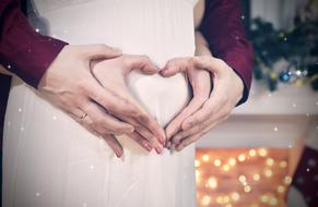 Couple, holding hands, in the beautiful heart shape on the belly