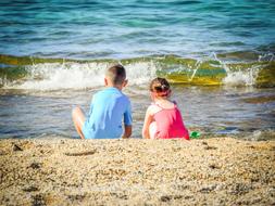Children play on sand beach at sea