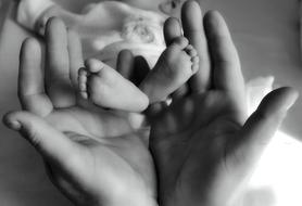 Black and white photo of the parent touching feet of the baby