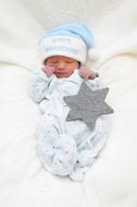 Cute baby in blue and white Christmas clothing and hat, and with gray star