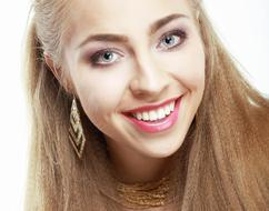 Smiling, blonde girl, with the make-up, earrings and necklace, in light