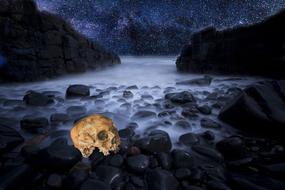 golden skull on stones in the fog on the background of rocks