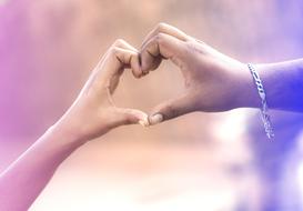 Couple holding hands in heart shape at colorful background