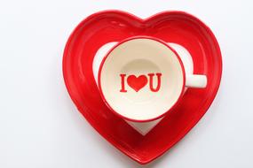 cup with the inscription I love you on a heart-shaped plate