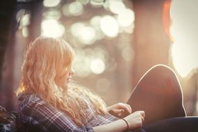 girl sitting on a bench in the forest during sunset on a blurred background