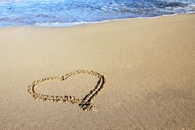 drawing heart on the beach sand on a sunny day