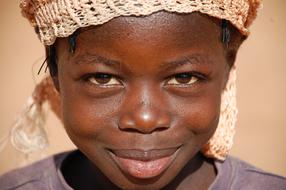 Portrait of the smiling child in cap, in light