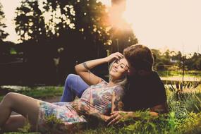 Couple, laying among the beautiful and colorful plants in sunlight