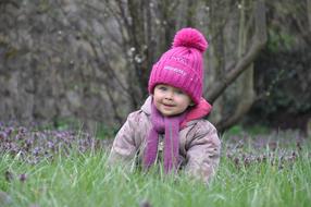 little girl in a pink hat on green grass