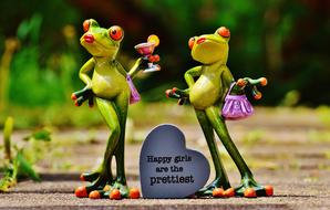 funny figurines of happy frogs on a blurred background