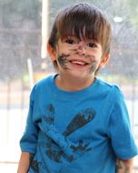 happy boy with dirty face on blurred background