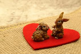 Cute and beautiful, brown figures of the Easter bunnies, on the red heart