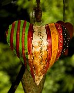 Close-up of the beautiful and colorful, shiny heart with patterns, among the plants in the garden