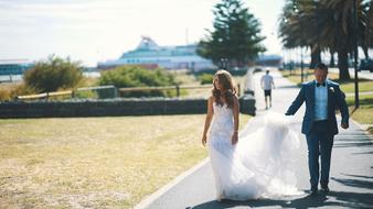 the bride and groom are walking along the road