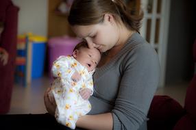 happy mom with newborn on blurred background