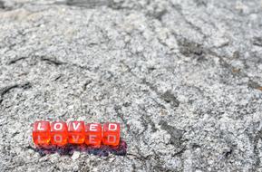 Shiny, red cubes with white "LOVED" sign, on the stones in light