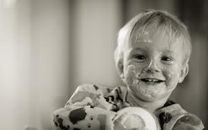 little child in yogurt on a blurred black and white background