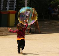 child with a huge soap bubble in the park