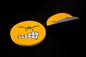 Post it notes with yellow, angry smileys, on the black surface