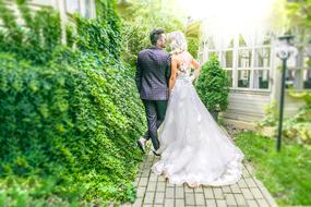 groom with bride near green bushes