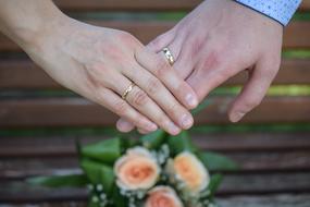 gold rings on the hands of the groom with the bride on the background of the wedding bouquet