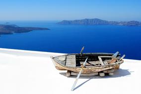 Colorful boat on the coast of Santorini, Greece, in sunlight, near the beautiful and colorful mountains