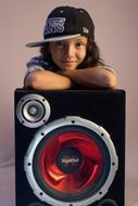 Portrait of the smiling girl child in cap, behind the colorful speaker