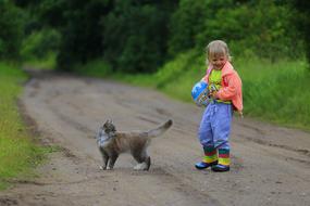 little girl next to the cat on the road