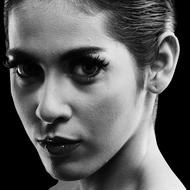 Black and white photo with the portrait of the beautiful woman with make-up. in light, at black background