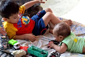 Two cute children playing with colorful toys, on the floor