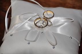 gold wedding rings on white pillow