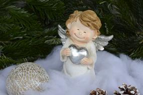 Beautiful, colorful and cute figure of the Christmas Angel, among the decorations, near the green fir tree