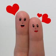 Two fingers with faces, in couple in love, among the red hearts