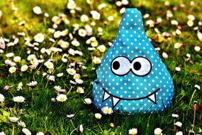 toy blue monster on chamomile field