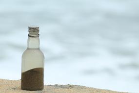bottle of sand on the beach on a blurred background
